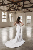 Vestido de noiva sereia da Luuly Noivas, destacando-se pela elegância e sofisticação em um espaço minimalista e luminoso. A silhueta é valorizada pela luz natural, enquanto a renda delicada adiciona um charme atemporal. Encontre o vestido ideal para seu dia especial conosco.