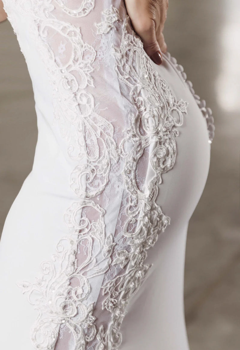 Este close-up do vestido de noiva Luuly Noivas revela a meticulosa arte da renda, com ornamentos que traçam a silhueta com sofisticação. A beleza está nos detalhes que prometem encantar e realçar a elegância no grande dia.